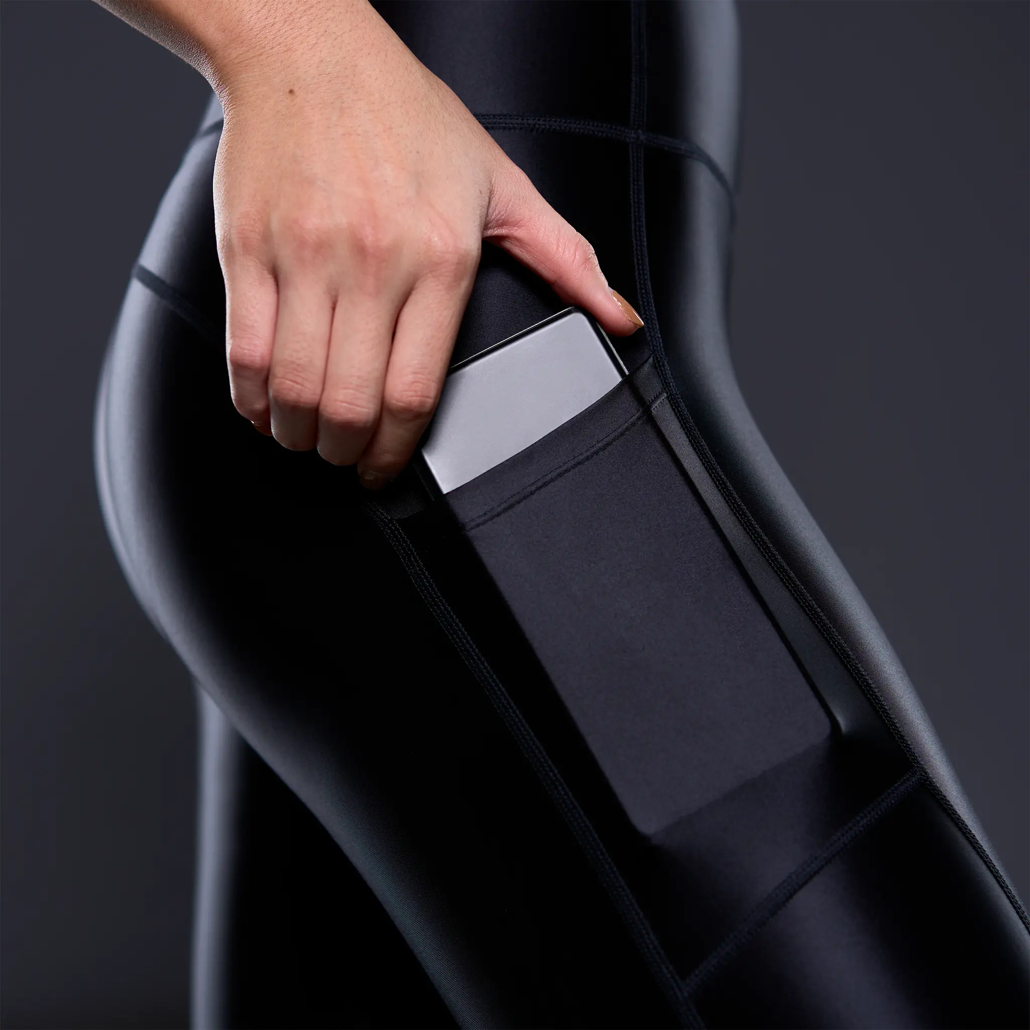 Black Powerracer sports leggings with integrated side pocket holding a smartphone.